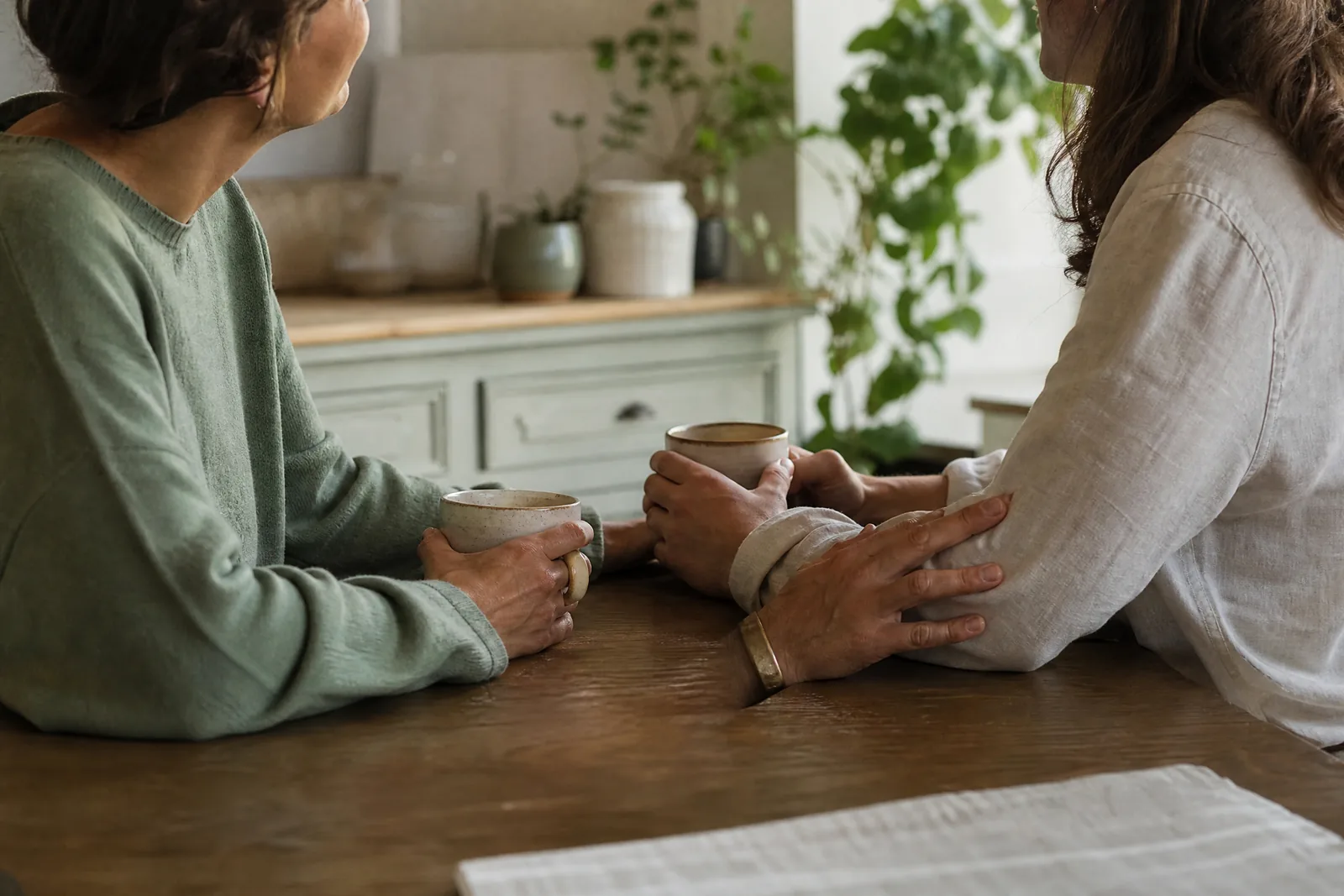 Two parents sitting together at a kitchen table sharing tea and conversation