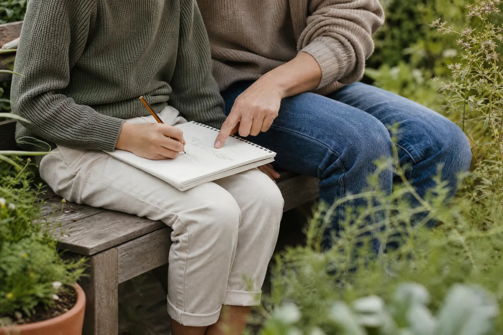Parent and child learning together outdoors on a garden bench with a notebook